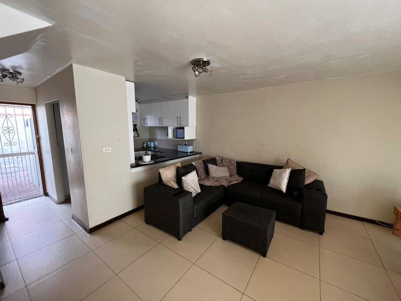 Open plan living area featuring tiled flooring and a compact kitchen with built-in cabinetry, providing a functional layout for modern living.