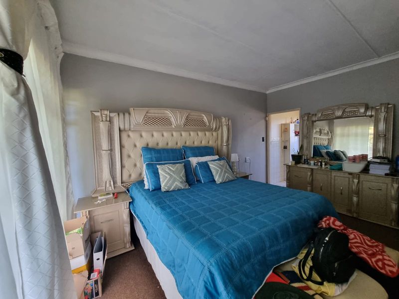A spacious bedroom featuring neutral wall tones, coved ceilings, and an adjoining en-suite bathroom access point.