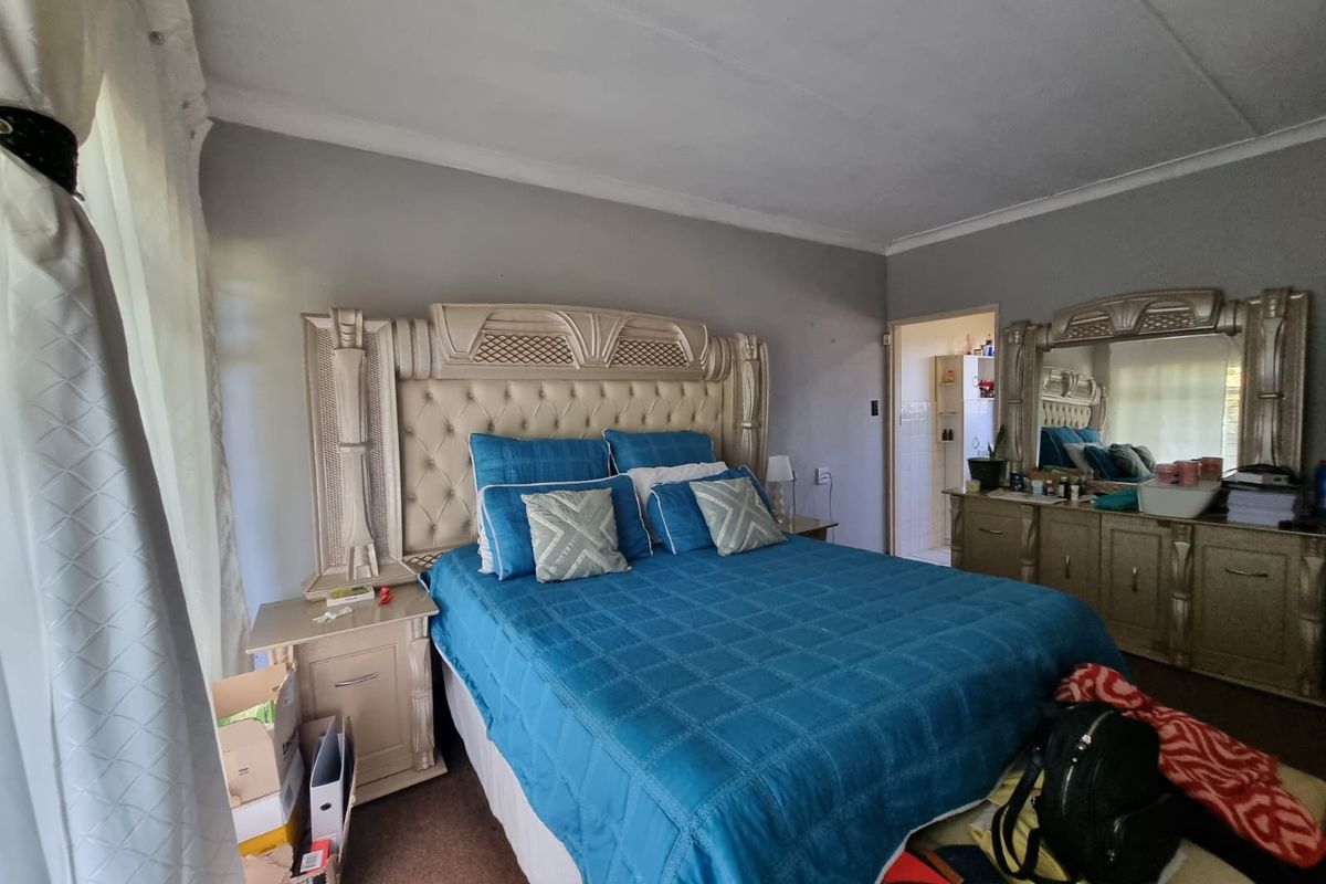 A spacious bedroom featuring neutral wall tones, coved ceilings, and an adjoining en-suite bathroom access point.