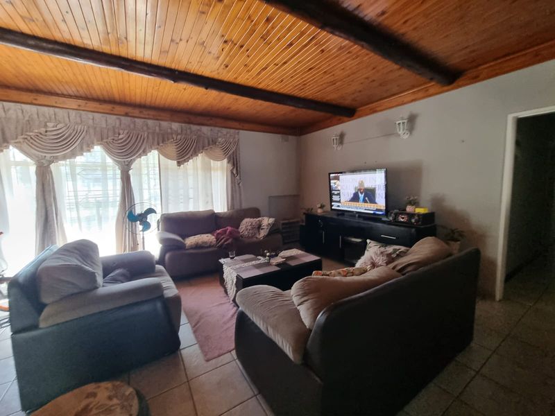 A living room featuring a distinctive exposed timber beam ceiling and tiled flooring, providing a cozy and traditional atmosphere.