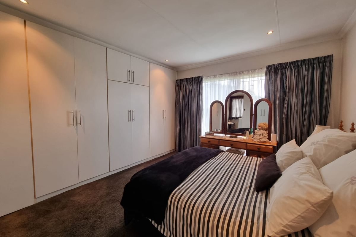 A well-maintained bedroom featuring extensive floor-to-ceiling built-in cupboards and recessed downlighting, providing ample storage and a clean, functional aesthetic.