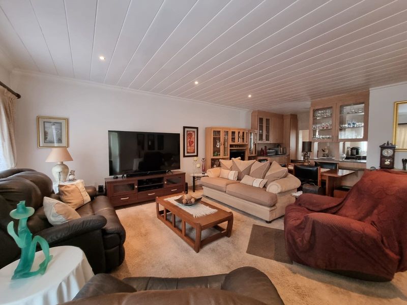 Spacious open-plan living area featuring a distinctive panelled ceiling, recessed lighting, and integrated built-in cabinetry for storage and display.