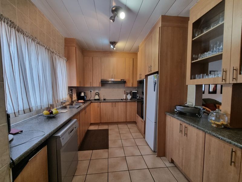 A functional kitchen featuring laminate cabinetry, granite countertops, built-in oven, extractor fan, and tiled flooring with ample storage space.
