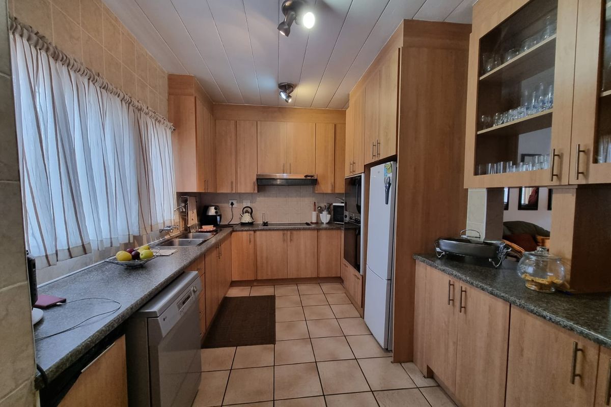 A functional kitchen featuring laminate cabinetry, granite countertops, built-in oven, extractor fan, and tiled flooring with ample storage space.