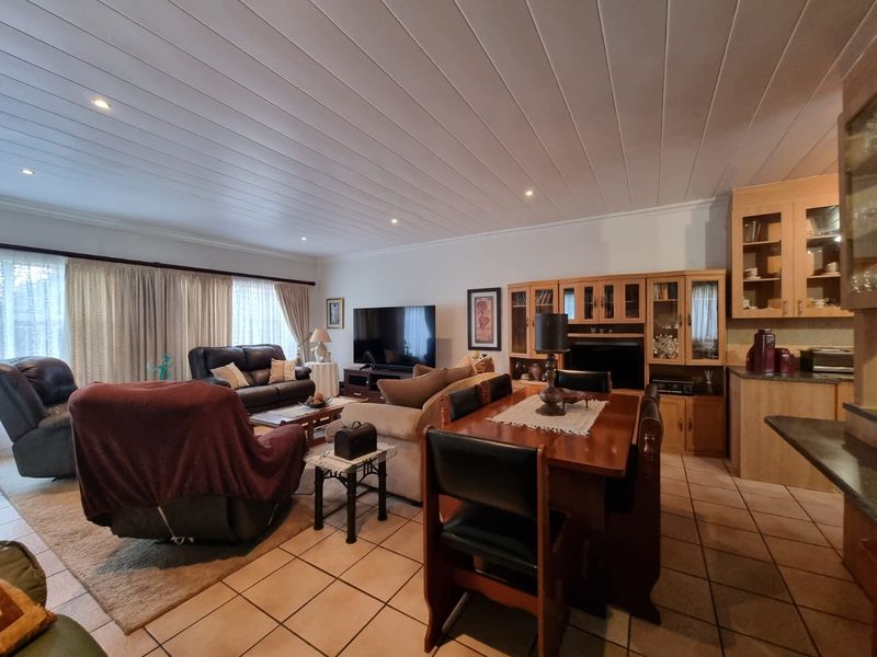 Spacious open-plan living and dining area featuring tiled floors, recessed lighting, and built-in cabinetry, offering a functional layout for family living.