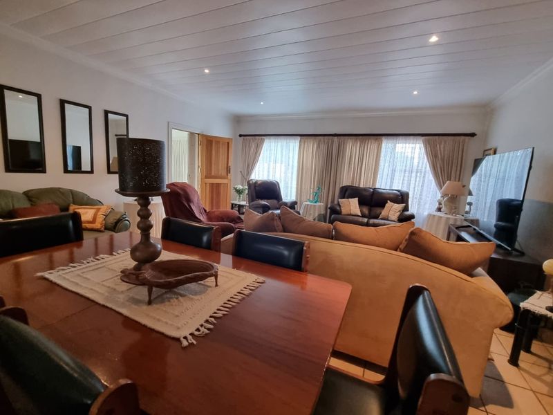 Spacious open-plan living and dining area featuring tiled flooring, recessed downlighting, and a distinctive timber panelled ceiling.