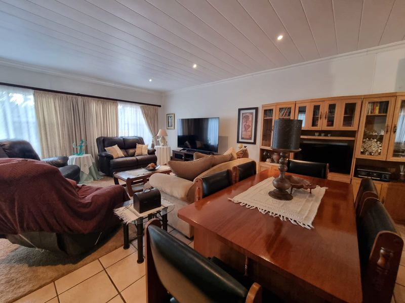 Spacious open-plan living and dining area featuring tiled flooring, recessed lighting, and built-in wooden cabinetry, offering a functional and comfortable layout.