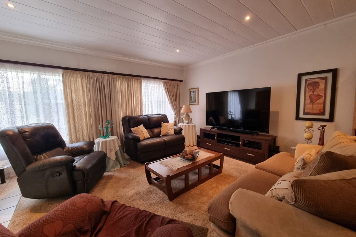 A comfortable living room featuring a tongue and groove ceiling with recessed lighting and large windows dressed with curtains.