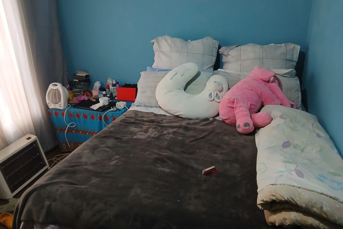 A bedroom featuring blue painted walls and natural light from a side window.