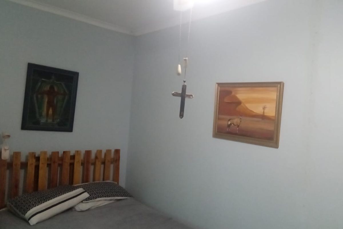 A bedroom featuring light-colored walls and a ceiling-mounted light fixture.