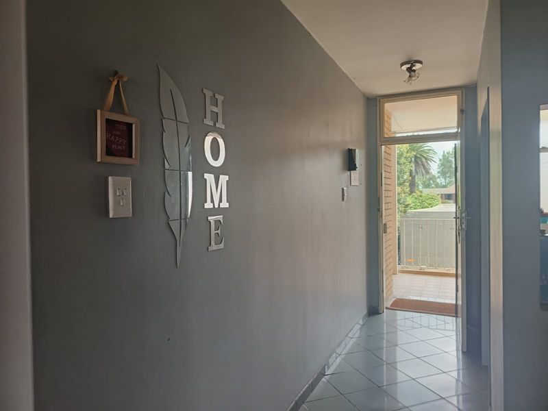 A bright entrance hallway featuring tiled flooring and a glass-paneled door leading to an outdoor balcony area.
