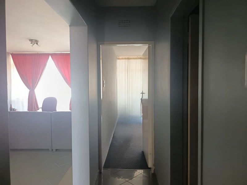 A functional hallway connecting living spaces, featuring tiled flooring and neutral wall finishes, providing access to adjacent rooms.