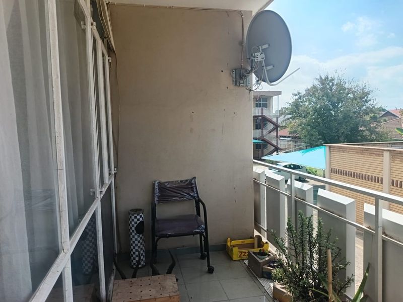 A functional balcony area featuring tiled flooring, a metal balustrade, and a wall-mounted satellite dish, offering an outdoor space for the flat.