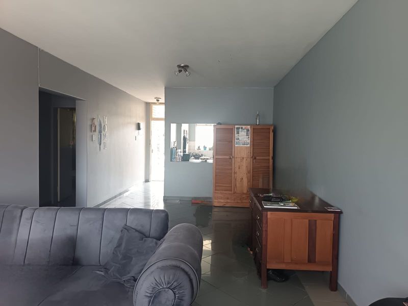 Open-plan living area featuring tiled flooring and a convenient pass-through window connecting to the kitchen space.
