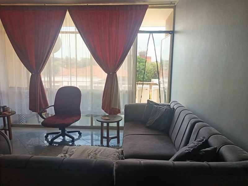 A living room featuring tiled flooring and a large sliding glass door providing access to the balcony area.