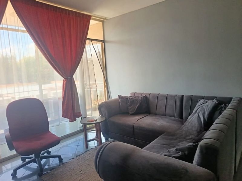 A living room area featuring tiled flooring and a large sliding glass door providing access to an outdoor space.