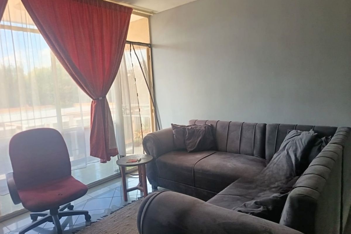A living room area featuring tiled flooring and a large sliding glass door providing access to an outdoor space.