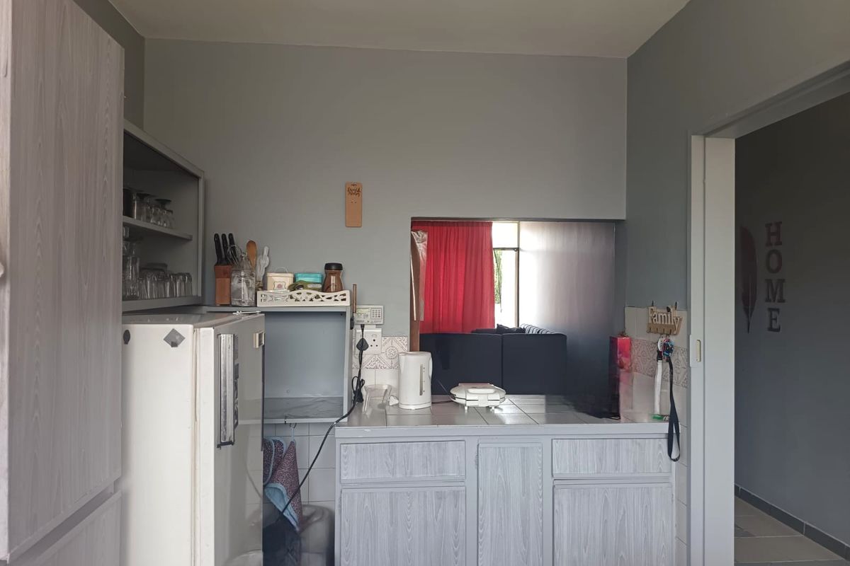 A functional kitchen area featuring built-in cabinetry, a tiled countertop, and a convenient pass-through window connecting to the adjacent living space.