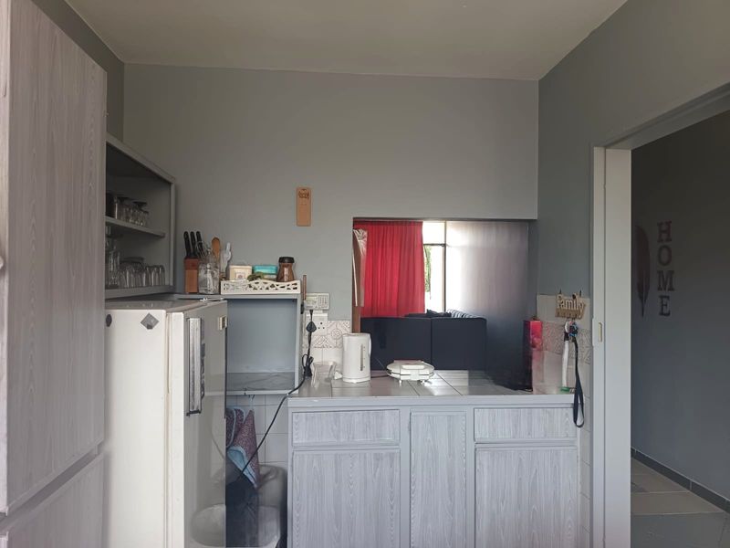 A functional kitchen area featuring built-in cabinetry, a tiled countertop, and a convenient pass-through window connecting to the adjacent living space.