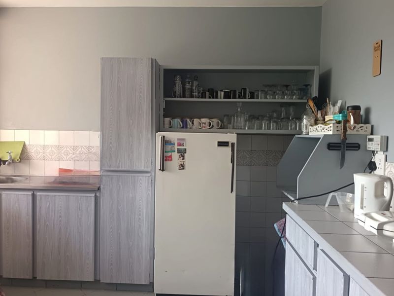 A functional kitchen featuring built-in cabinetry, tiled countertops, and a tiled backsplash, offering a practical layout for daily use.