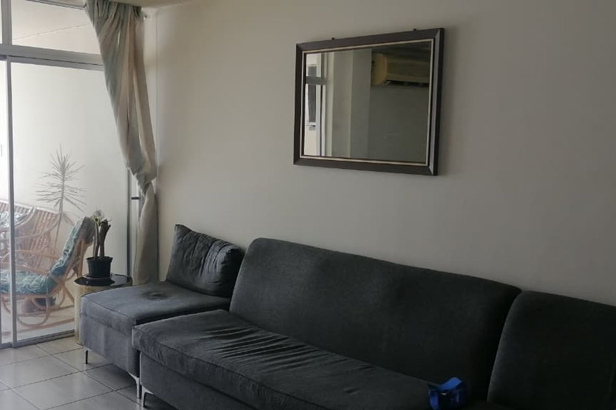 A living room featuring tiled flooring and large sliding glass doors that provide access to an outdoor patio area.