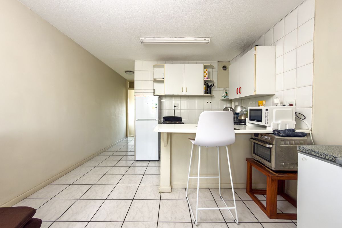 A functional kitchen area featuring tiled flooring, a tiled backsplash, and built-in cabinetry, offering a practical layout for daily use.
