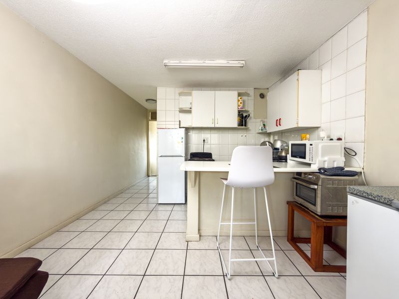 A functional kitchen area featuring tiled flooring, a tiled backsplash, and built-in cabinetry, offering a practical layout for daily use.