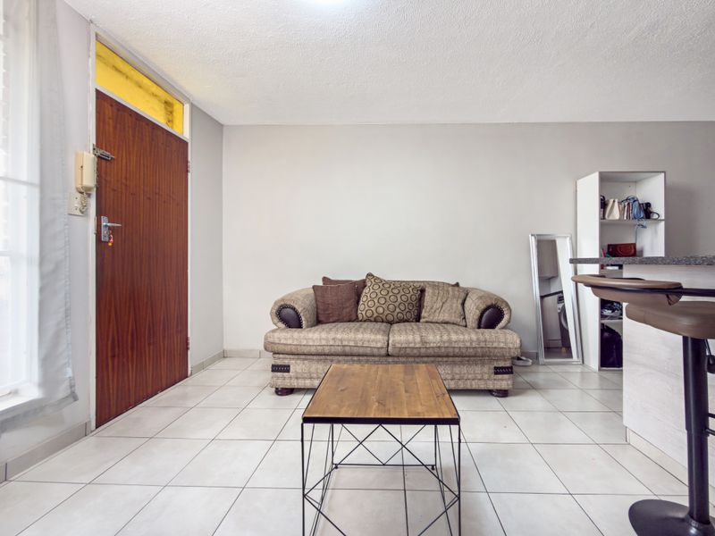 Open plan living area featuring tiled flooring, a timber entrance door with transom window, and a built-in shelving unit.