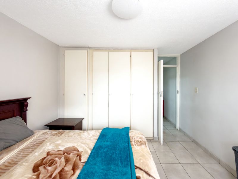 A bedroom featuring built-in cupboards and tiled flooring, offering a functional space with neutral wall tones.