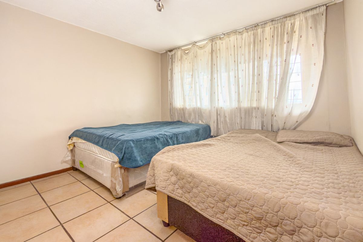 A bedroom featuring tiled flooring and neutral wall finishes, offering a functional space ready for modernization and personal styling.