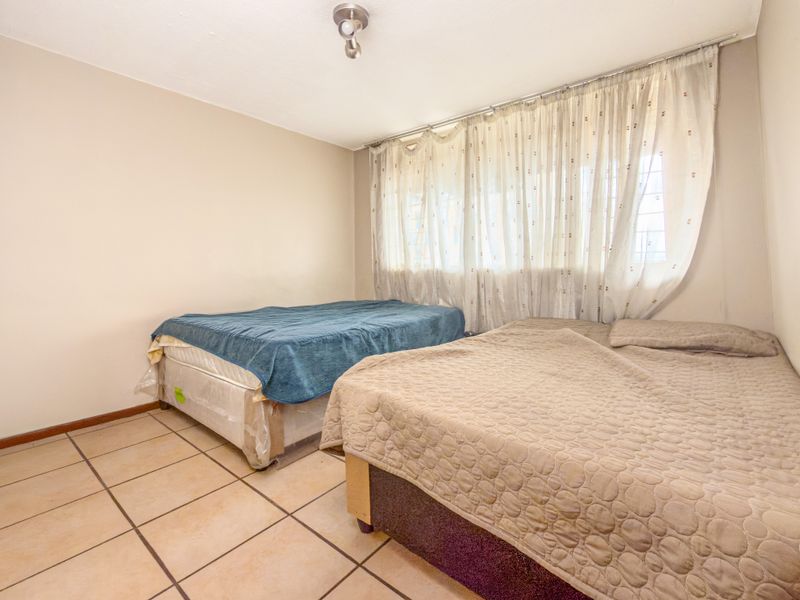 A bedroom featuring tiled flooring and neutral wall finishes, offering a functional space ready for modernization and personal styling.