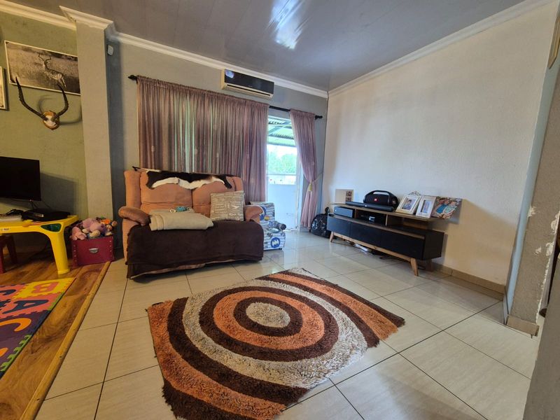 A living room featuring tiled flooring, a wall-mounted air conditioning unit, and a sliding glass door providing access to the exterior.