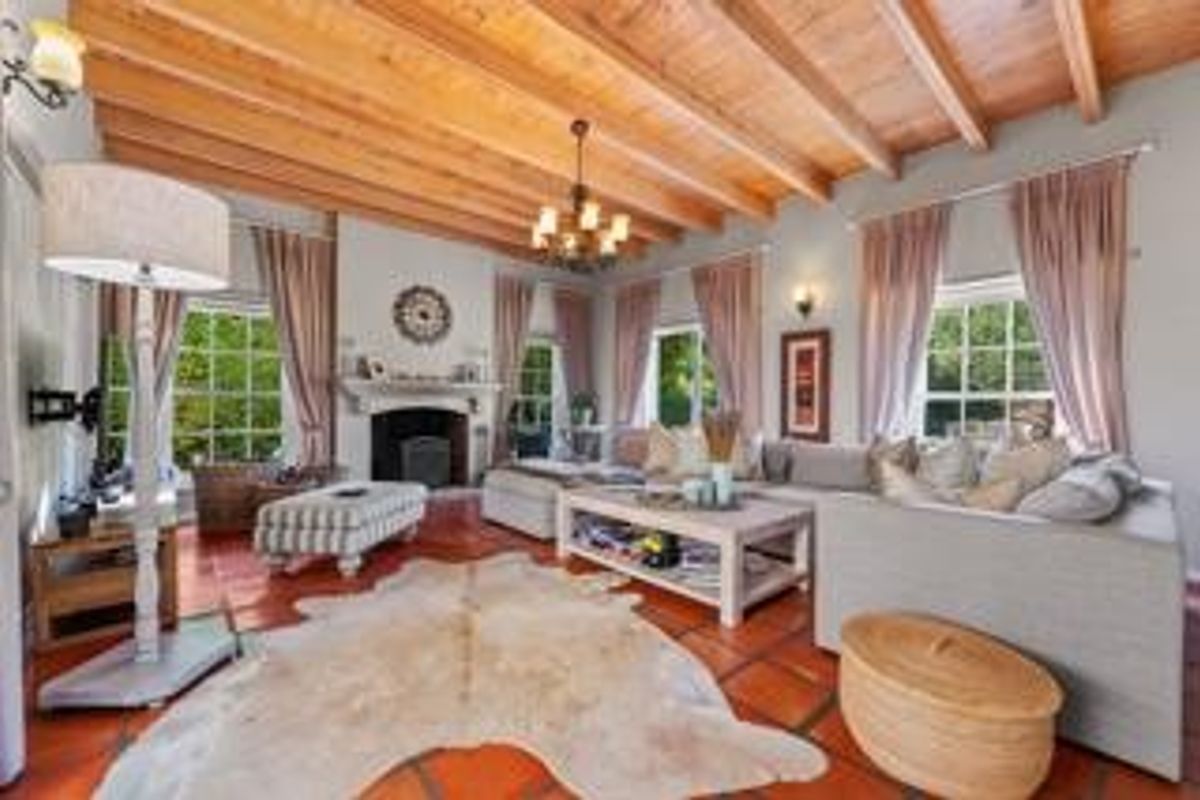 Spacious living room featuring exposed timber beam ceilings, terracotta floor tiles, and a traditional fireplace, creating a warm and inviting atmosphere.