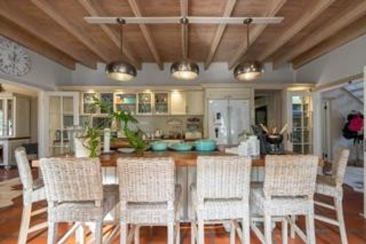 A well-appointed kitchen featuring a central island with bar seating, exposed timber beam ceiling, and integrated cabinetry.