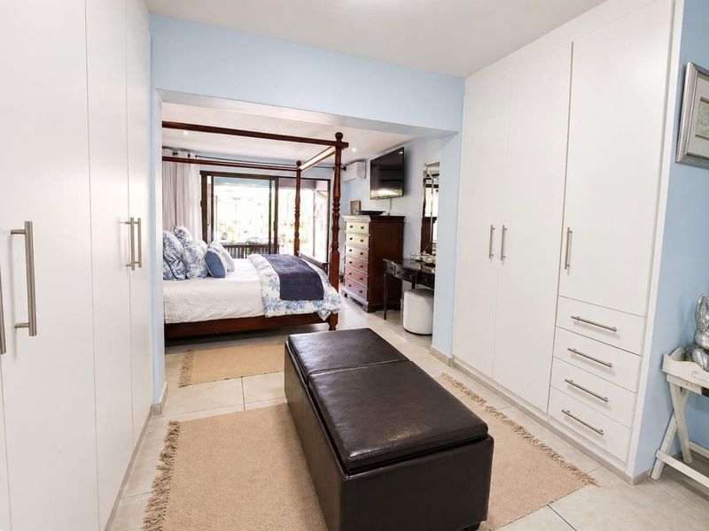Spacious bedroom featuring extensive built-in cupboard storage, tiled flooring, and sliding glass doors leading to an outdoor area.