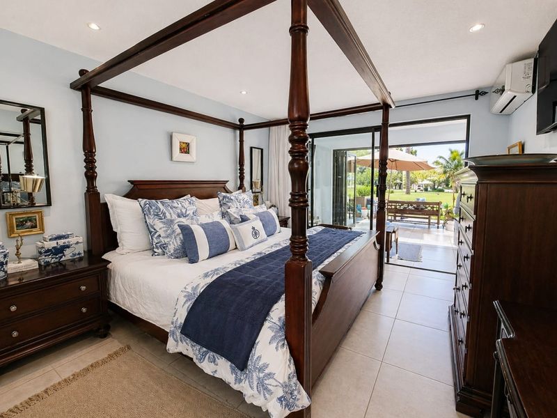 Spacious bedroom featuring tiled flooring, recessed lighting, and large sliding glass doors providing direct access to the outdoor patio area.