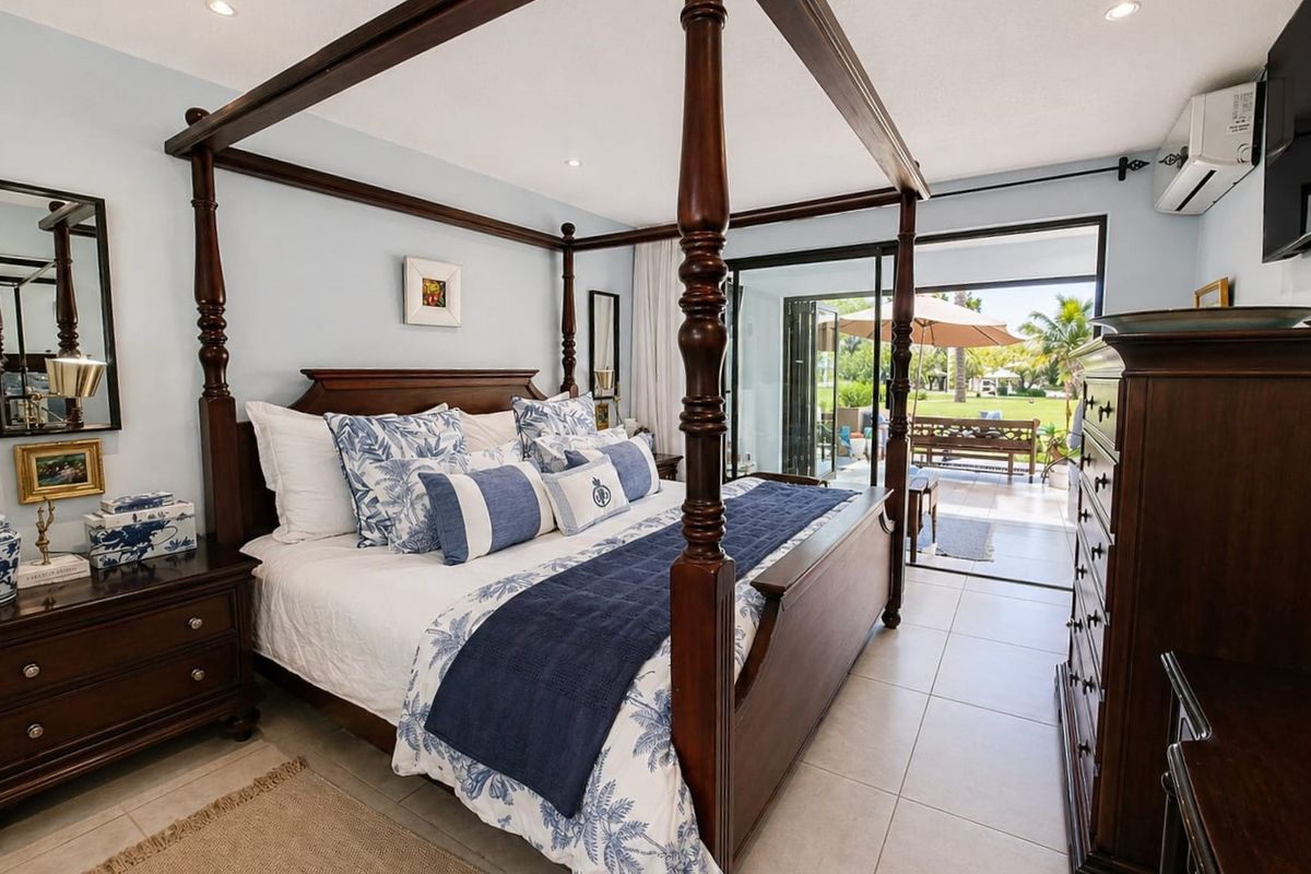 Spacious bedroom featuring tiled flooring, recessed lighting, and large sliding glass doors providing direct access to the outdoor patio area.