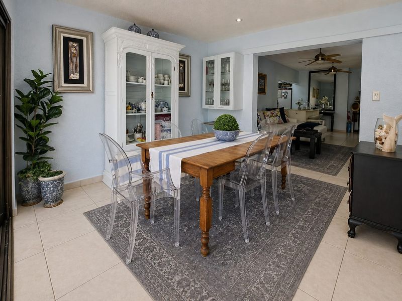 A bright dining area featuring tiled flooring, recessed lighting, and built-in cabinetry, seamlessly flowing into the adjacent living space.