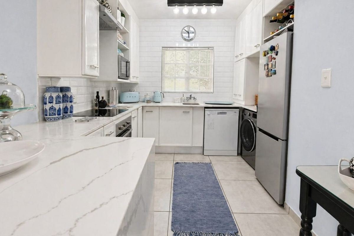 A well-maintained kitchen featuring white cabinetry, stone countertops, subway tile backsplash, and integrated appliances, offering a clean and functional workspace.