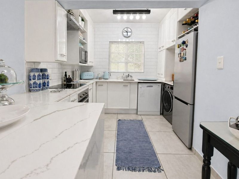 A well-maintained kitchen featuring white cabinetry, stone countertops, subway tile backsplash, and integrated appliances, offering a clean and functional workspace.