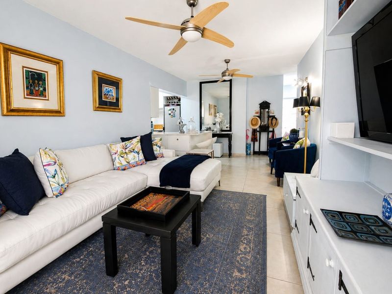 A bright open-plan living area featuring tiled flooring, dual ceiling fans, and a functional kitchen island, creating a cohesive and inviting space.