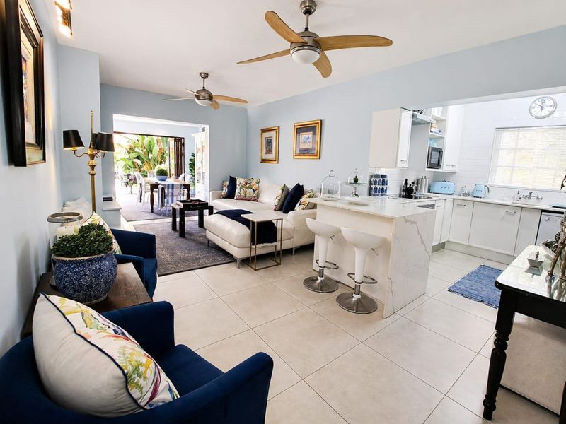 Spacious open-plan living area featuring a modern kitchen with stone island, tiled floors, and seamless flow to an outdoor patio through sliding glass doors.