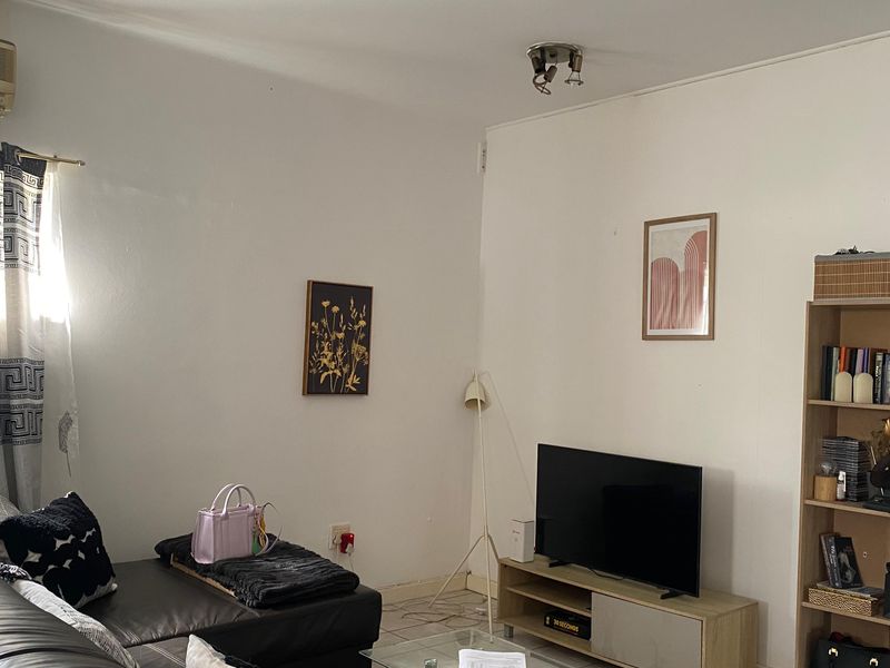 A living room area featuring tiled flooring, a wall-mounted air conditioning unit, and a ceiling-mounted spotlight fixture.