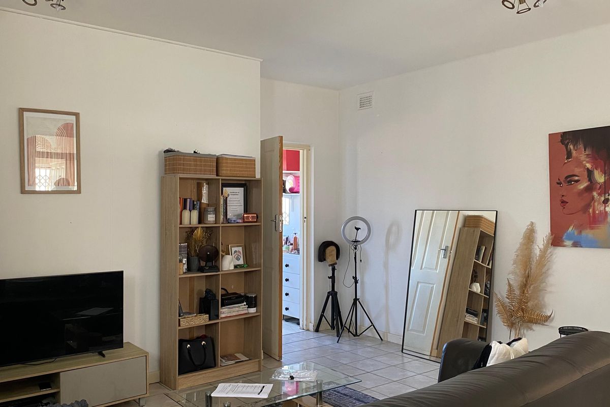 A living room featuring tiled flooring and neutral wall finishes, providing a functional space with access to an adjacent room.