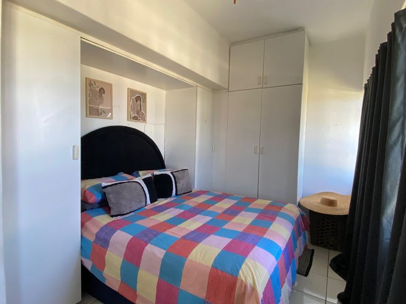 A bedroom featuring built-in cupboards and tiled flooring, offering functional storage space.