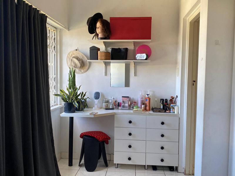 A bedroom featuring tiled flooring, a security gate on the window, and built-in shelving units.