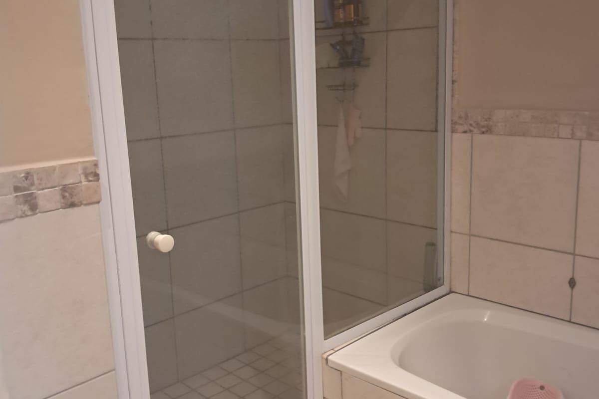 A functional bathroom featuring a built-in bathtub and a separate glass-enclosed shower with tiled walls and flooring.