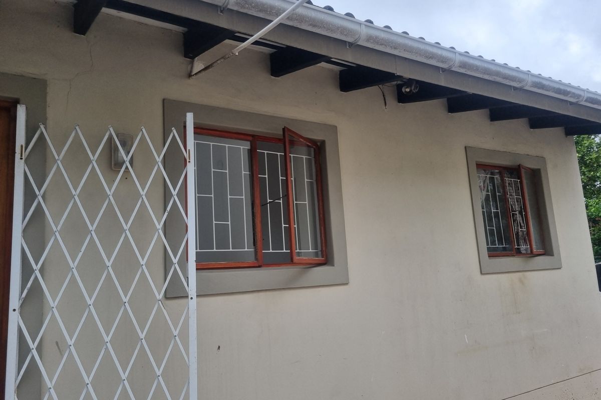 Exterior view of the property featuring timber window frames with security bars, exposed rafters, and guttering along the roofline.