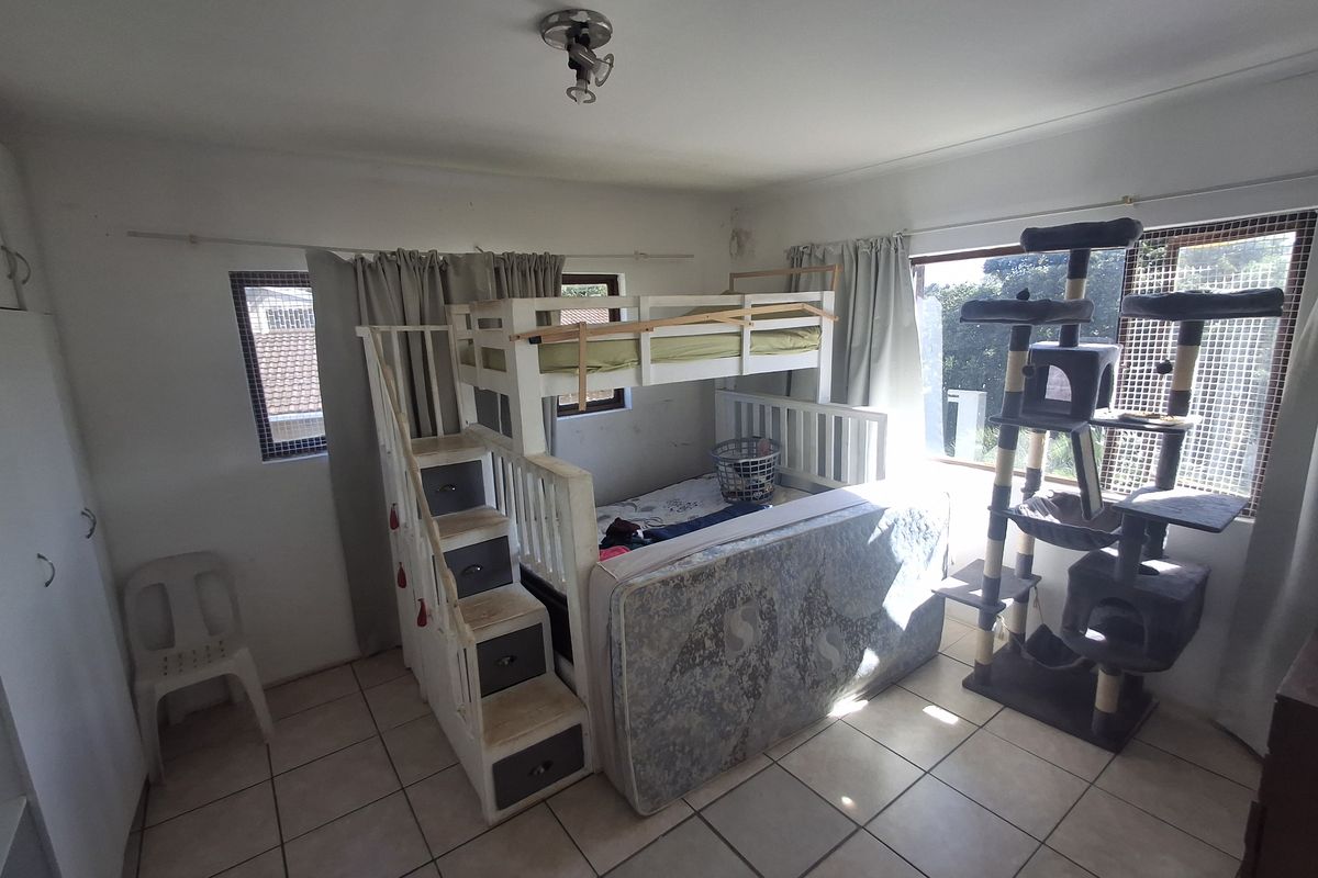 A functional bedroom featuring tiled flooring, built-in storage, and large windows allowing for natural light.