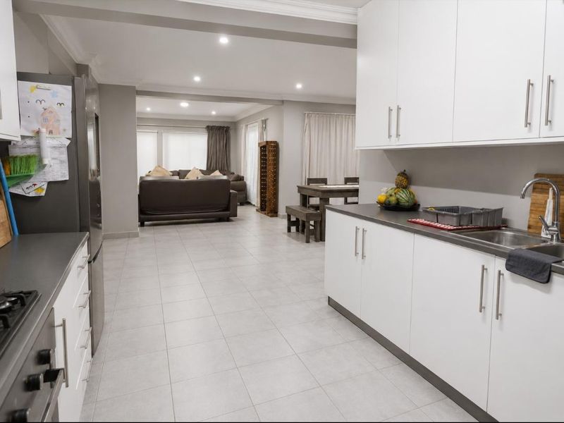 Spacious open-plan kitchen and living area featuring modern white cabinetry, tiled flooring, and recessed lighting, creating a bright and functional living space.